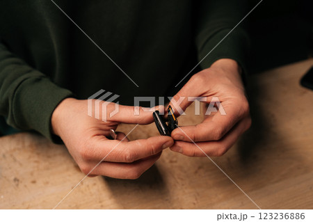 Closeup hands of unrecognizable technician male carefully opening smartwatch to replace battery, demonstrating intricate process of device repair. Concept of process electronic device maintenance. 123236886