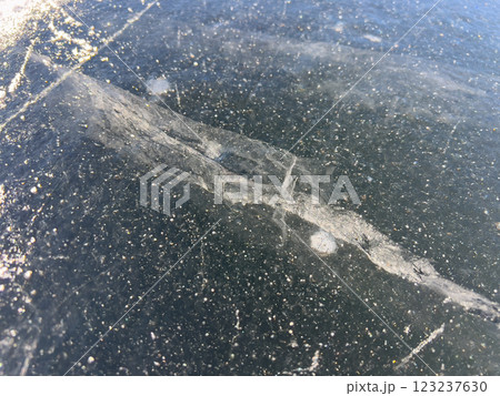 A close-up view of a frozen surface with visible cracks and bubbles, capturing the intricate details and natural patterns of the ice. A close-up view of a frozen surface with visible cracks and bubbles, capturing the intricate details and natural patterns of the ice. 123237630