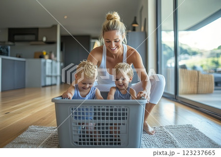 A woman and two children sit in a laundry basket of stuffed animals 123237665