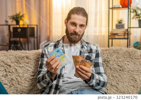 Young man counting money euro cash at home, bill check, confident smile, financial comfort, salary Young man counting money euro cash at home, bill check, confident smile, financial comfort, salary 123240170