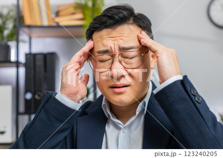 Tired Asian business man suffering from headache problem tension, migraine, stress at home office Tired Asian business man suffering from headache problem tension, migraine, stress at home office 123240205
