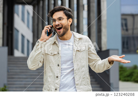 Happy surprised Indian man involved in pleasant conversation phone call good news enjoying talking Happy surprised Indian man involved in pleasant conversation phone call good news enjoying talking 123240208