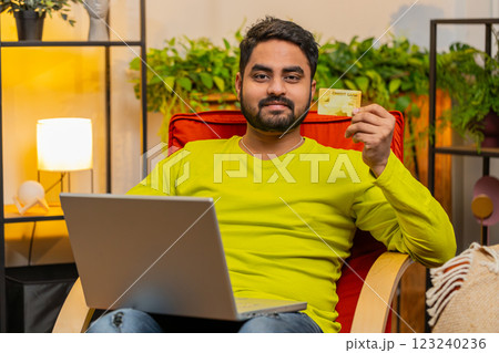 Indian man using credit bank card and laptop, transferring money, purchases online shopping at home 123240236