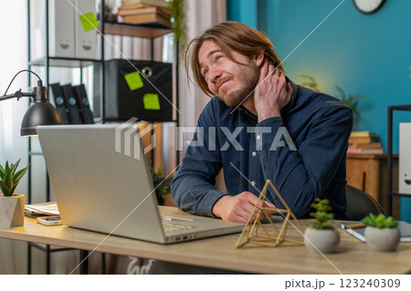 Business man freelancer overworking suffers from spine neck muscle pain at home office workplace 123240309