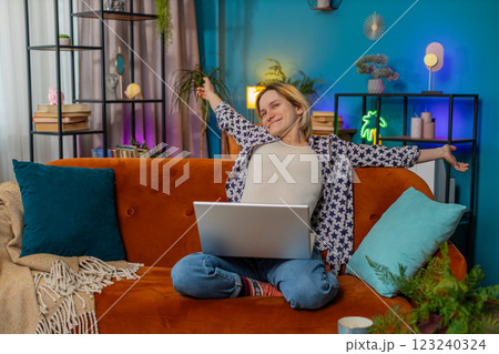 Happy young relaxed woman girl sitting on couch after finishing work on laptop in living room 123240324