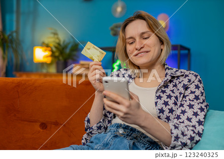 Happy woman doing payments online purchase shopping in internet store holding banking credit card 123240325