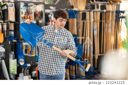 Guy choosing a shovel in the store Guy choosing a shovel in the store 123241225