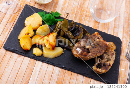 Fried lamb leg steaks with potatoes and padron peppers on slate board Fried lamb leg steaks with potatoes and padron peppers on slate board 123241590
