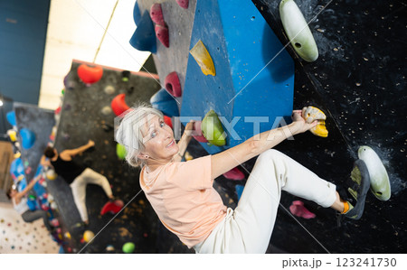Determined old lady doing difficult wall climb in climbing gym Determined old lady doing difficult wall climb in climbing gym 123241730