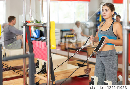 Young woman training her arms using straps Young woman training her arms using straps 123241928