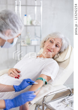 Female doctor doing injection to sleepy tired old woman in clinic. Female doctor doing injection to sleepy tired old woman in clinic. 123242254