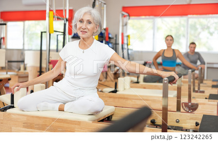 Senior woman performs exercise on reformer to improve coordination, balance, and posture 123242265