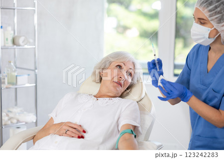 Young doctor drawing blood from elderly patient. Young doctor drawing blood from elderly patient. 123242283