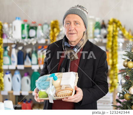 Elderly man choosing a festive shower set in a Christmas supermarket Elderly man choosing a festive shower set in a Christmas supermarket 123242344