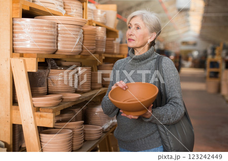 Aged woman choosing earthenware crockery in store Aged woman choosing earthenware crockery in store 123242449
