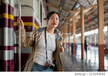 Asian woman carrying a camera is looking around while coming down from the carriage at train station 123243682