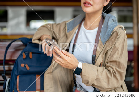 close up of asian woman looking ahead and holding phone while sitting on the wooden benchmark. close up of asian woman looking ahead and holding phone while sitting on the wooden benchmark. 123243690