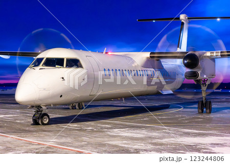 Close-up of a white passenger turboprop aircraft taxis through an airport at dusk 123244806