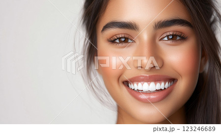 Radiant woman with a bright, beautiful smile showcasing her natural beauty against a plain background with soft, diffused lighting. 123246689
