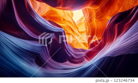 Abstract sand formations of a canyon. The stone walls curve and wind, lit by sunlight in shades of orange, purple, and blue. 123246734