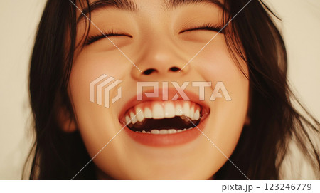 Radiant happiness: Close-up of a joyful woman with closed eyes and a wide, infectious smile showing healthy white teeth. 123246779