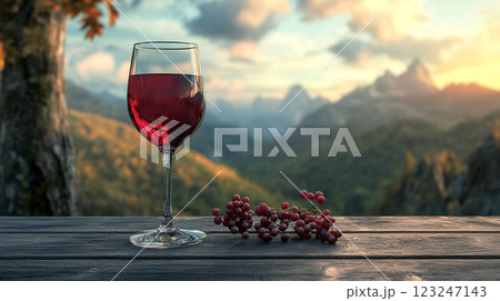 Wine with stunning views. Enjoying a glass of wine on a wooden table with a grape and beautiful mountain background. Wonderful time to relax. 123247143