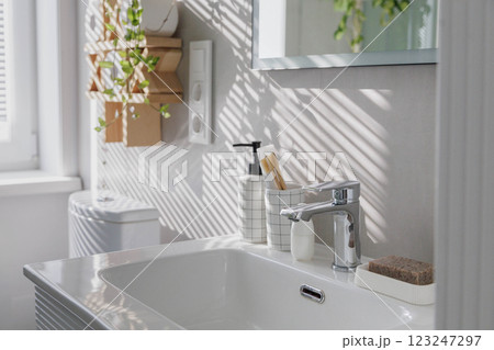 Stylish clean white bathroom with light gray tiles on the walls and lots of indoor plants. 123247297