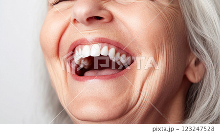 An older woman laughs heartily, showcasing her white teeth and facial wrinkles that are visible as she smiles, showing pure joy. 123247528