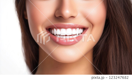 Radiant smile showcasing bright, healthy teeth and glossy lips against a blurred background, with a glimpse of brown hair, exuding confidence. 123247682