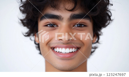 Radiant smile of a young man with dark curly hair, showcased against a clean white backdrop, radiating positivity and health. Radiant smile of a young man with dark curly hair, showcased against a clean white backdrop, radiating positivity and health. 123247697