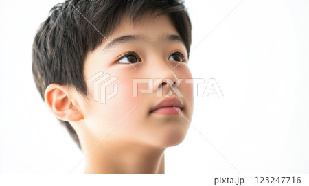 Portrait of a young boy with a hopeful expression, gazing upwards. His skin has a soft, delicate quality with a clean, bright background. 123247716