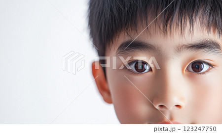 Close-up view reveals a young boy's face with soft lighting, capturing the innocence and clarity in his dark brown eyes and features. Close-up view reveals a young boy's face with soft lighting, capturing the innocence and clarity in his dark brown eyes and features. 123247750
