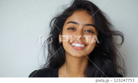Radiant smile portrait of a young woman with long, dark, flowing hair, showcasing natural beauty against a neutral background. Radiant smile portrait of a young woman with long, dark, flowing hair, showcasing natural beauty against a neutral background. 123247753