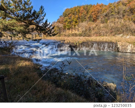 river waterfall with stones, bridge and forest 123250035