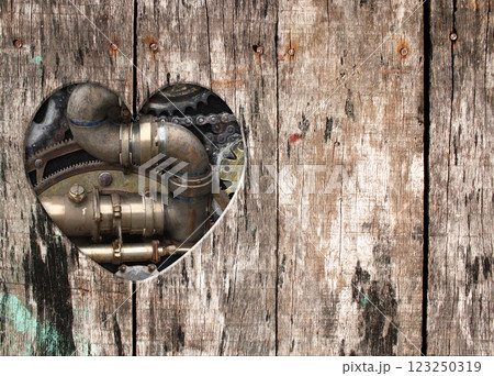 Retro background in steampunk style with heart-shaped hole in wooden boards and vintage metal machine details, pipeline, gear. Copy space for text. Can be used for industrial, mechanical design 123250319