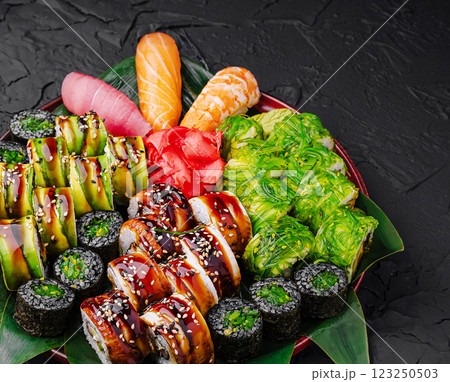 Sushi platter featuring assorted rolls and sashimi on a dark surface Sushi platter featuring assorted rolls and sashimi on a dark surface 123250503