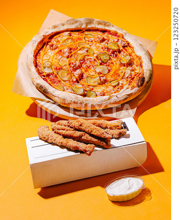 Delicious pizza and chicken strips on a vibrant orange background Delicious pizza and chicken strips on a vibrant orange background 123250720