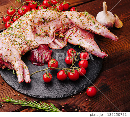 Freshly prepared rabbit with herbs and cherry tomatoes on wood Freshly prepared rabbit with herbs and cherry tomatoes on wood 123250721