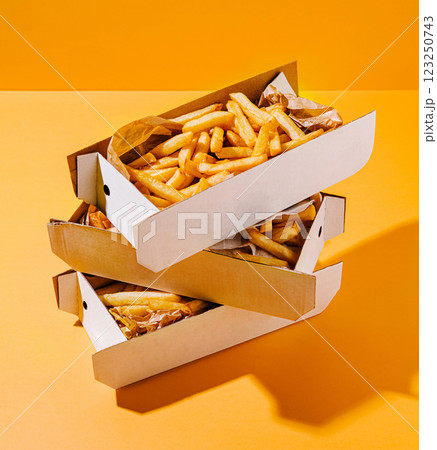 Delicious golden fries stacked in boxes against vibrant background Delicious golden fries stacked in boxes against vibrant background 123250743
