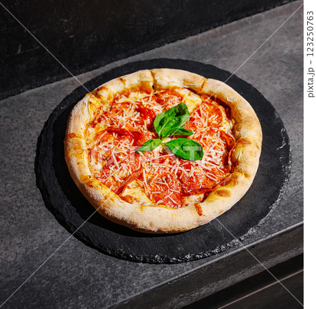Delicious hot pizza served on slate plate in modern restaurant Delicious hot pizza served on slate plate in modern restaurant 123250763