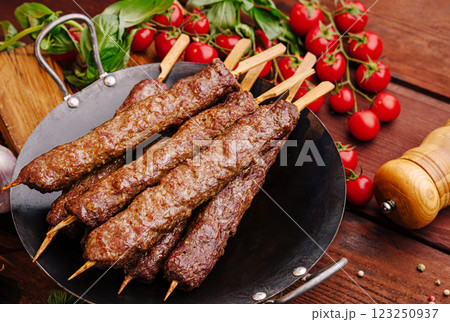 Grilled skewered meat with fresh tomatoes on a wooden table 123250937