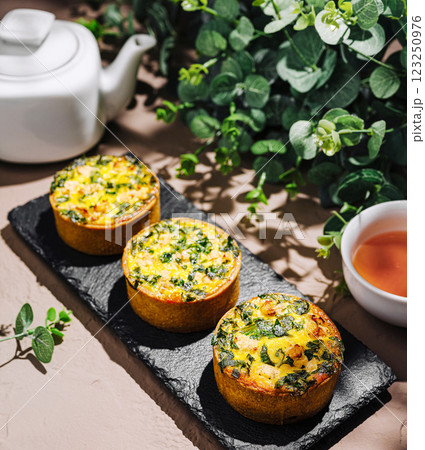 Savory mini quiches with spinach and herbs on a rustic table Savory mini quiches with spinach and herbs on a rustic table 123250976