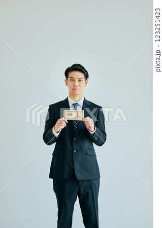 一万円札を持つ20代の若い男性 一万円札を持つ20代の若い男性 123251423