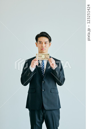 一万円札を持つ20代の若い男性 一万円札を持つ20代の若い男性 123251424