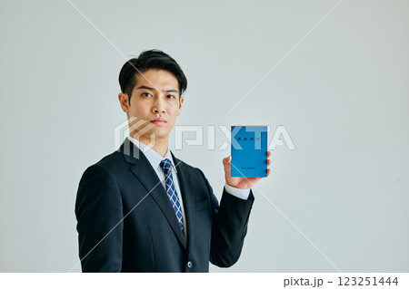 年金手帳を持つ20代の若い男性 123251444