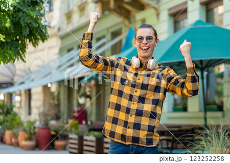 Excited happy young man tourist celebrating success, winning good news victory on urban city street 123252258