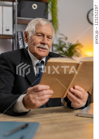 Bored Caucasian senior businessman reading book, literature, taking a rest after work at table Bored Caucasian senior businessman reading book, literature, taking a rest after work at table 123252297