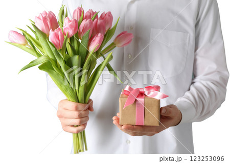 8 March, International Women's Day, a man in a white shirt with a bouquet of pink tulips and a gift box in his hands, isolated on white background, PNG 123253096