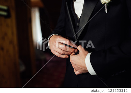 Groom in white shirt, suit and bow tie holding lapel of his jacket indoors. Wedding concept. 123253312