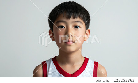 Youthful Portrait: A serene Asian child with short dark hair and a focused expression, wearing a athletic top against a plain backdrop. 123253863